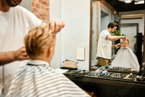 Barber cutting customer's hair in front of mirror at salon photo