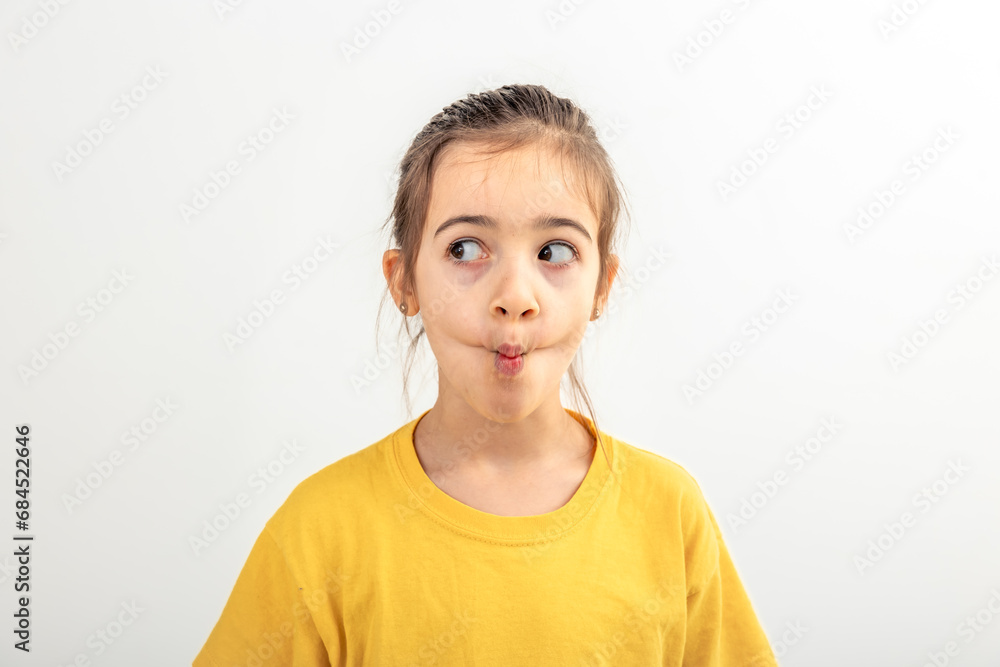 Little Caucasian girl makes funny faces on a white background isolated. Little Caucasian girl makes funny faces on a white background isolated.