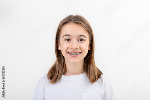 Brunette girl smiling with braces on her teeth on a white background isolated.