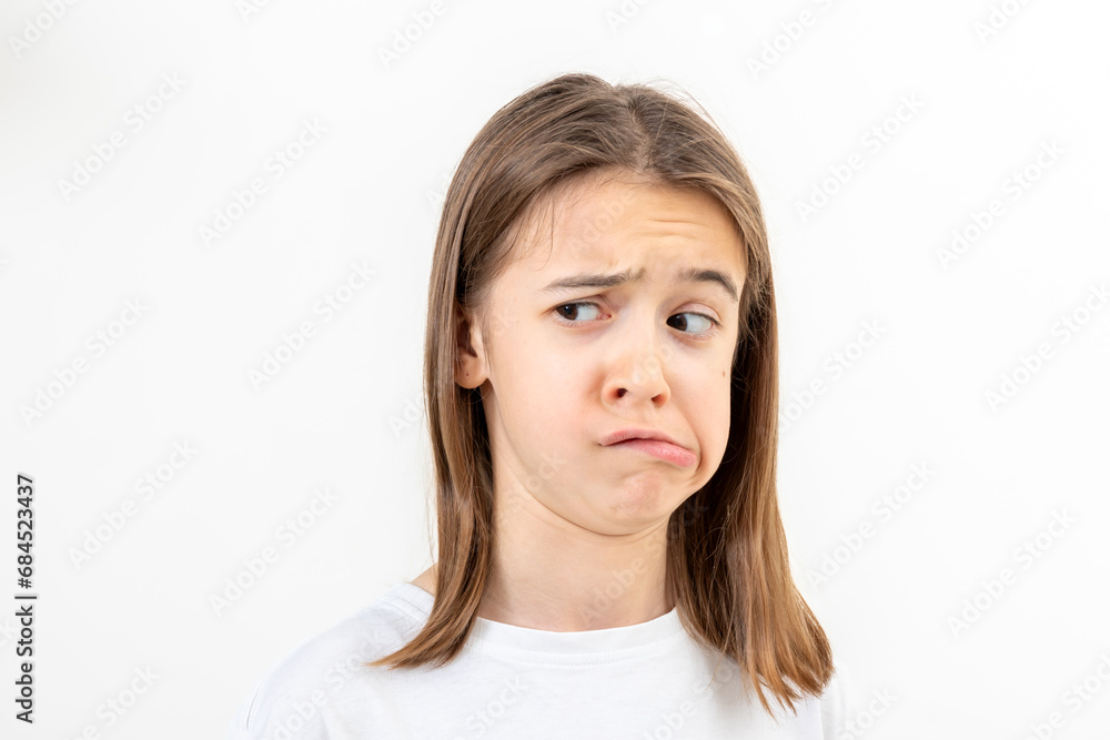 A teenage girl grimaces with displeasure on a white background, isolated. A teenage girl grimaces with displeasure on a white background, isolated.