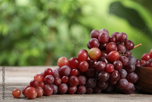 Delicious fresh red grapes on wooden table against blurred background, closeup. Space for text