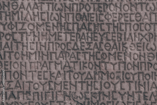 Retro text background. Fragment of ancient inscription (imperial law in ancient Greek language), carved on marble block. Monochrome. Ancient Miletus, Turkey (Turkiye). Ancient art and history concept photo