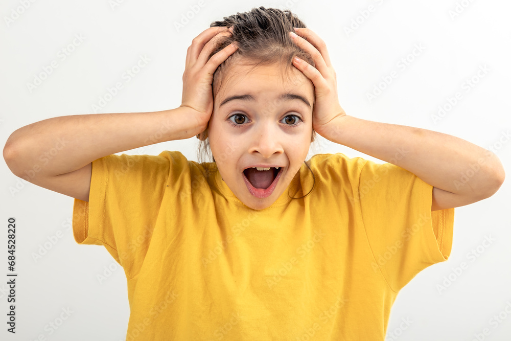 Little Caucasian girl in a yellow T-shirt holds her head on a white background. Little Caucasian girl in a yellow T-shirt holds her head on a white background.