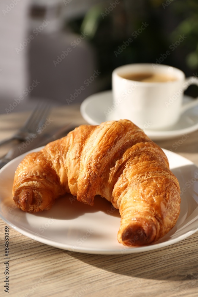 Delicious fresh croissant served on wooden table, closeup