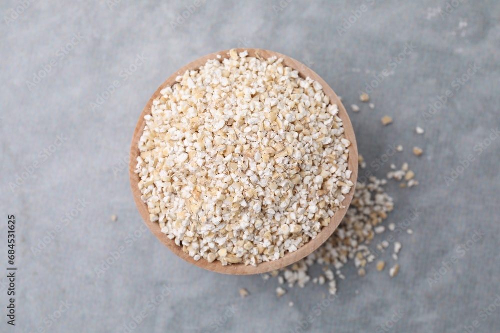 Raw barley groats in bowl on grey table, top view Raw barley groats in bowl on grey table, top view