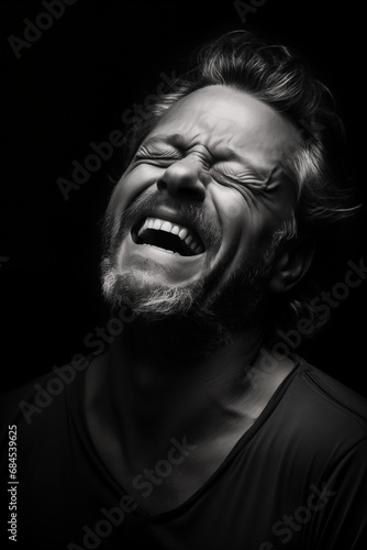 Expressive monochrome: A close-up portrait of a laughing mature European with his head thrown back Against a Black Background, capturing strong emotions in black and white