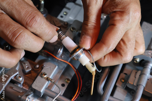 Close up of a technician's hand repairing a broken cooktop or stovetop