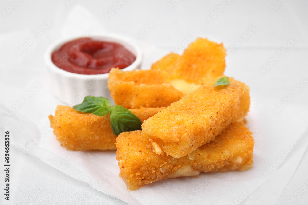 Tasty fried mozzarella sticks with basil leaves and ketchup on white table, closeup Tasty fried mozzarella sticks with basil leaves and ketchup on white table, closeup