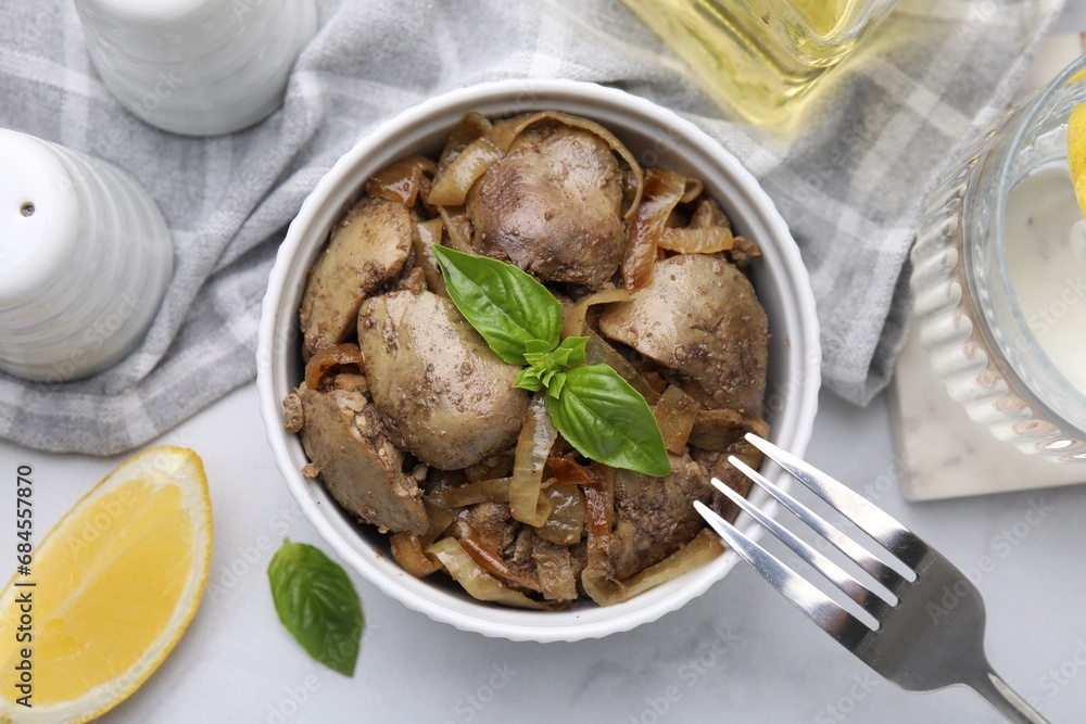 Delicious fried chicken liver with onion and basil served on white marble table, flat lay