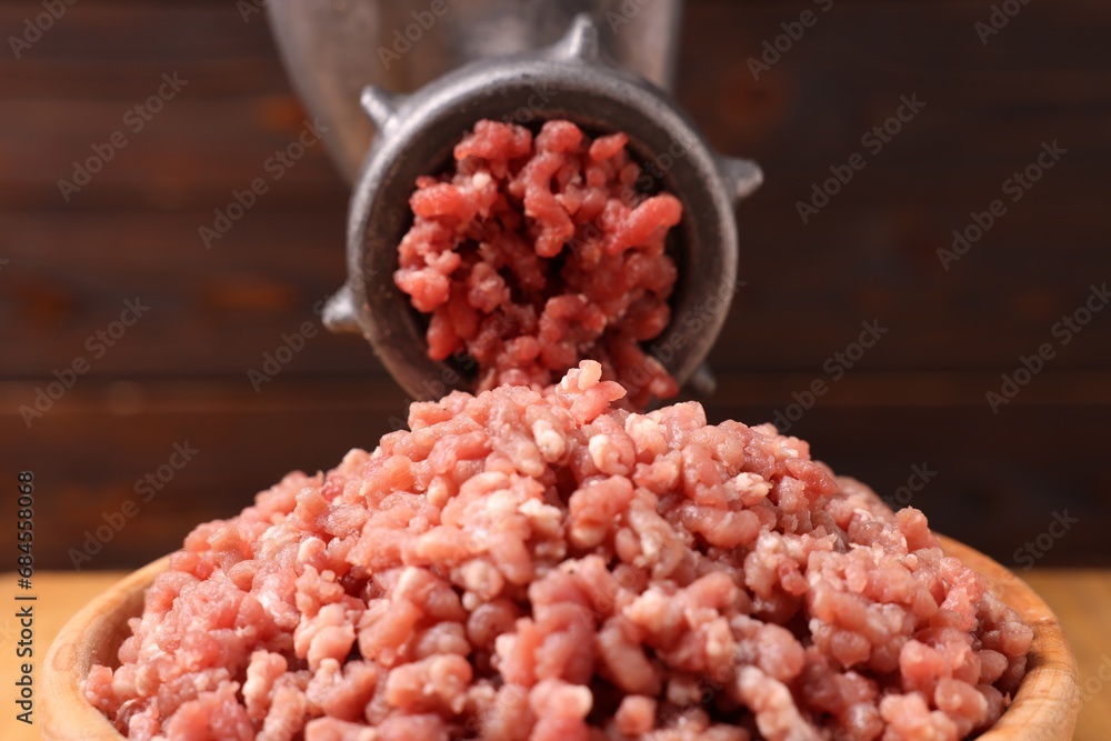 Manual meat grinder with beef mince against blurred background, closeup Manual meat grinder with beef mince against blurred background, closeup