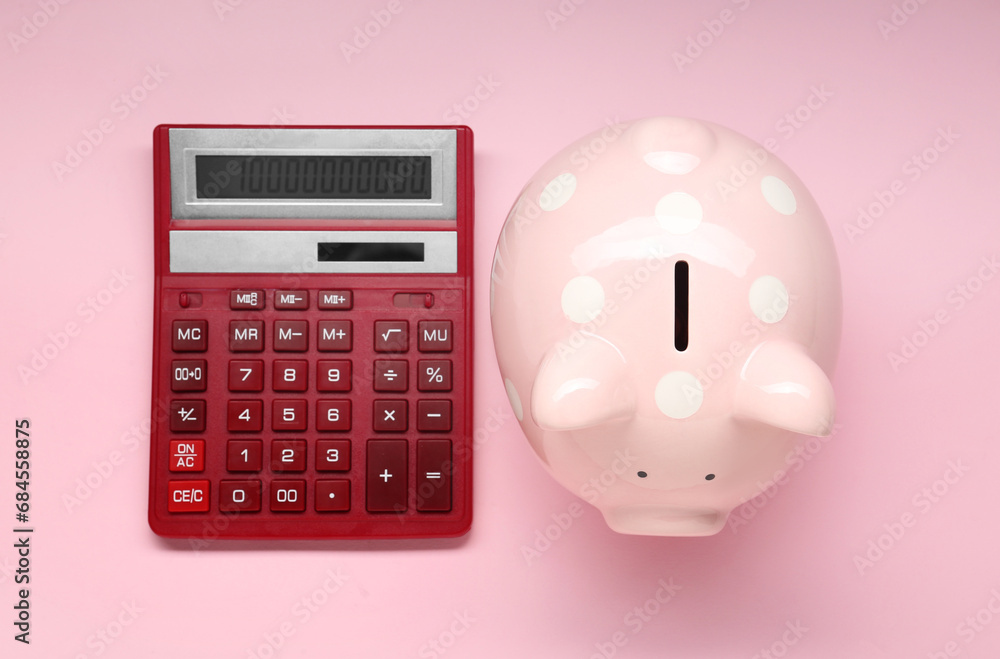 Calculator and piggy bank on pink background, top view Calculator and piggy bank on pink background, top view