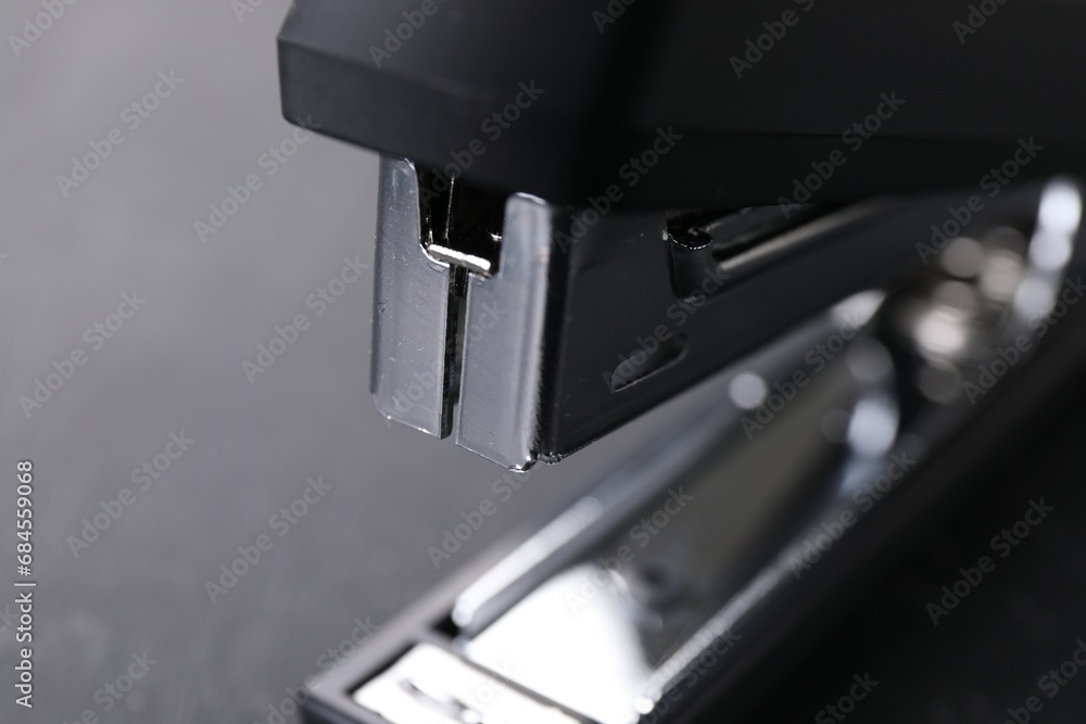 One black stapler on gray background, closeup One black stapler on gray background, closeup