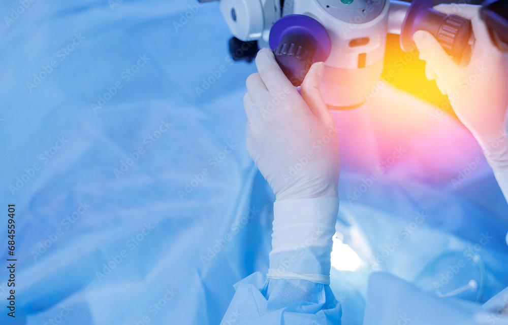 Fototapeta premium Lasik treatment. Laser vision correction. Doctor examines fundus in microscope, patient under sterile cover.
