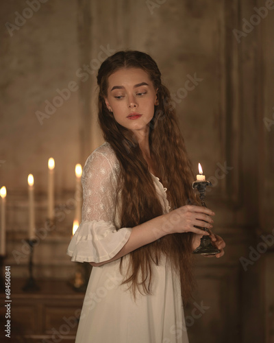 Portrait of a girl in a nightgown against a background of candles