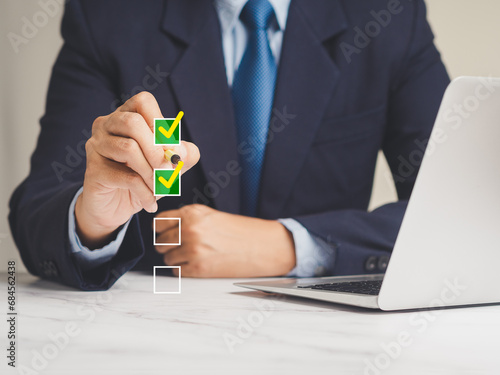 Businessman using a pen to tick the correct sign mark for quality control assurance of ISO concept. photo