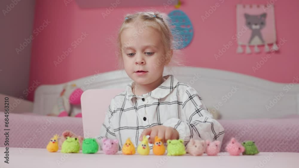 Girl child plays with small knitted animal toys in a room at home Girl child plays with small knitted animal toys in a room at home