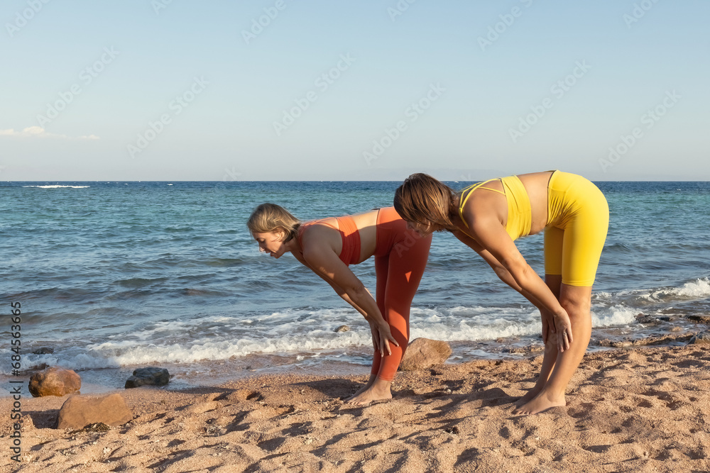 Fototapeta premium Yoga instructor with a student practice yoga on the beach