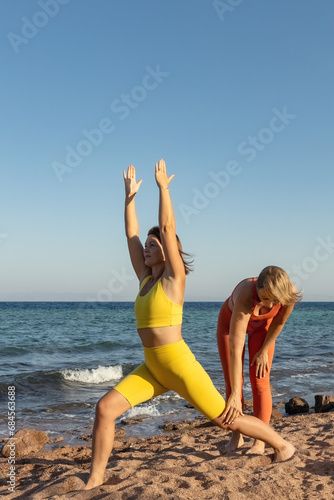 Yoga instructor with a student practice yoga on the beach