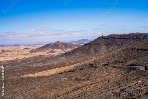 View of a road that runs through several mountains through the desert. Photography taken in Fuerteventura  Canary Islands  Spain.