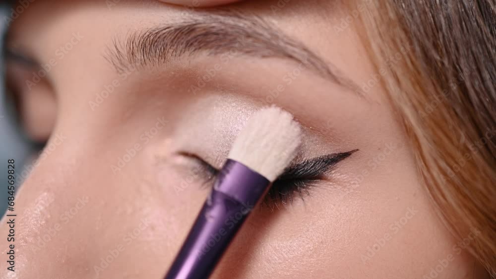 Professional makeup. The makeup artist applies the shadow to the eyelid with a brush. Extreme close-up. Professional makeup. The makeup artist applies the shadow to the eyelid with a brush. Extreme close-up.