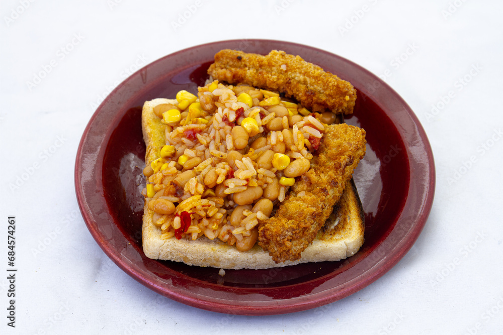 Fish portions with a rice and vegetable mix on a slice of white bread toast