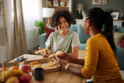 Mother and teenage son having pizza at home photo