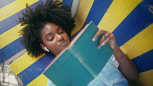 Foto Closeup teen reading book aloud lying on bench outdoors