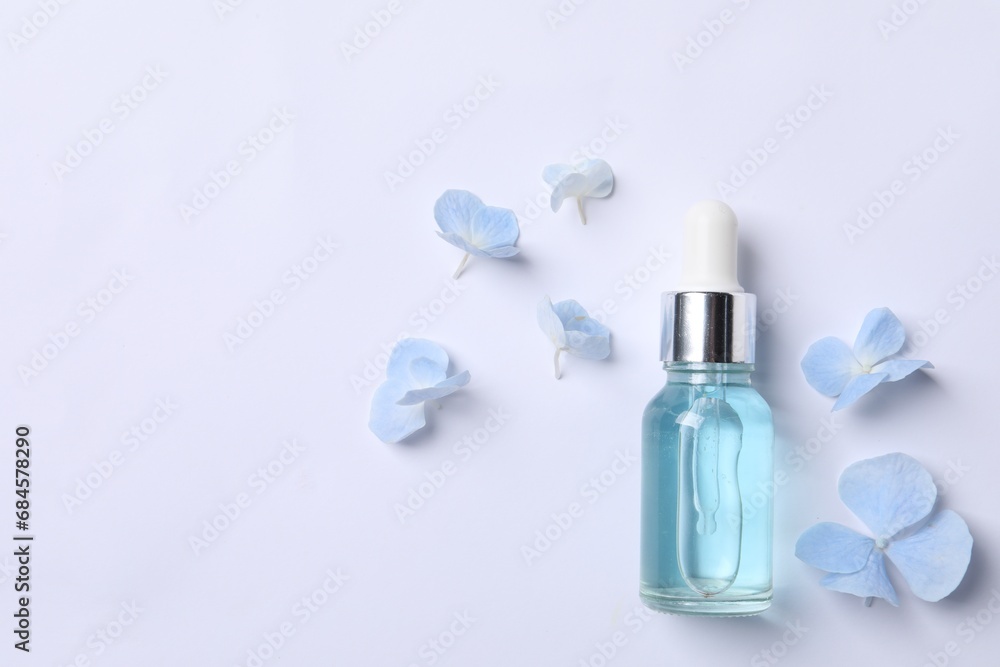 Bottle of cosmetic serum and beautiful flowers on white background, flat lay. Space for text Bottle of cosmetic serum and beautiful flowers on white background, flat lay. Space for text