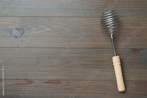 One metal whisk on wooden table, top view. Space for text