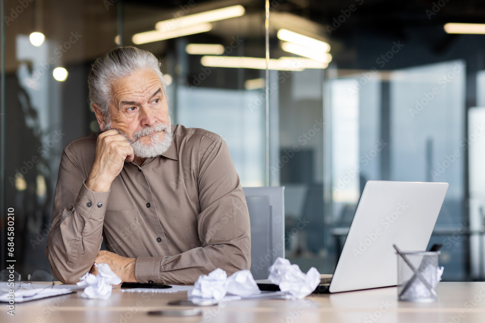 Upset frustrated gray haired boss sitting inside office at workplace, mature man old businessman in shirt working with laptop, unhappy with company achievement results and negative reports. Upset frustrated gray haired boss sitting inside office at workplace, mature man old businessman in shirt working with laptop, unhappy with company achievement results and negative reports.