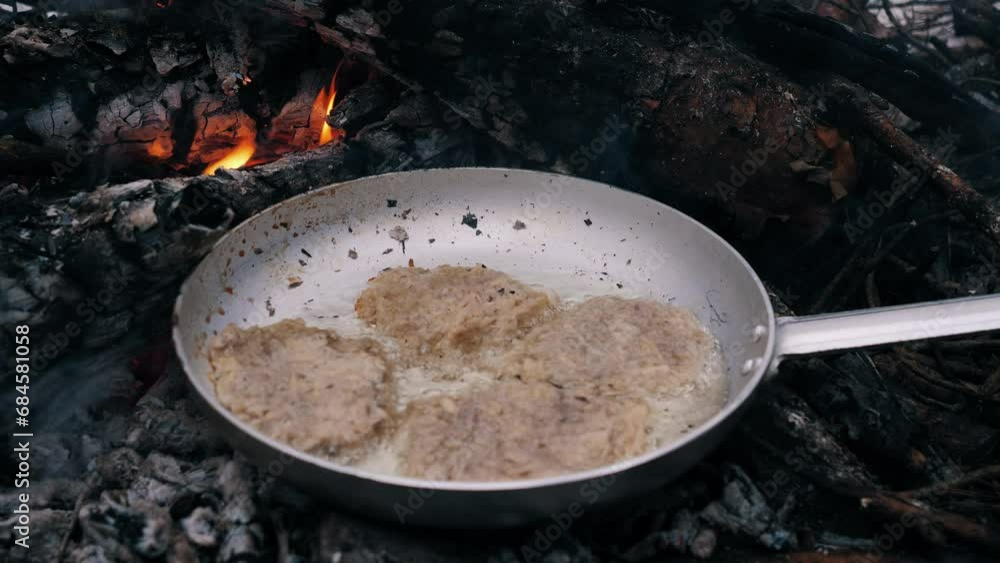 Cooking potato pancakes in a frying pan while camping in winter over a campfire 4k Cooking potato pancakes in a frying pan while camping in winter over a campfire 4k