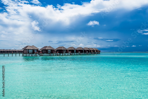 Scenic view of water villas in Maldives with turquoise water and dramatic sky
