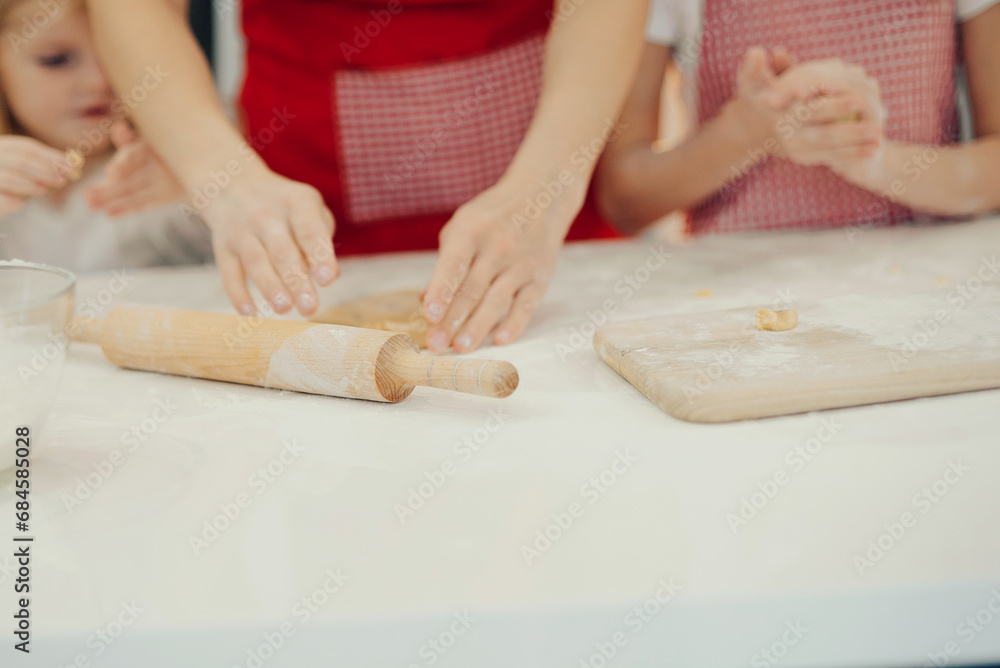 Mother and daughters making cookies at kitchen and having fun at home Mother and daughters making cookies at kitchen and having fun at home