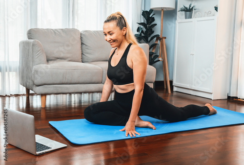 Senior woman in sportswear being doing yoga in meditation posture on exercising mat at home. Healthy senior pensioner lifestyle with peaceful mind and serenity. Clout