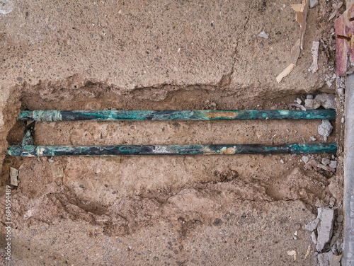 Exposed, leaking copper central heating pipes, badly corroded after being buried in the concrete floor slab of a house of around 60 years.