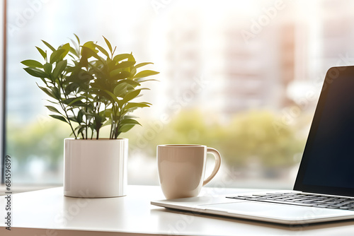 Close up view of comfortable office desk with laptop, mug, tree pot, office supplies and copy space on white table in glass partition office. Generative Ai. photo