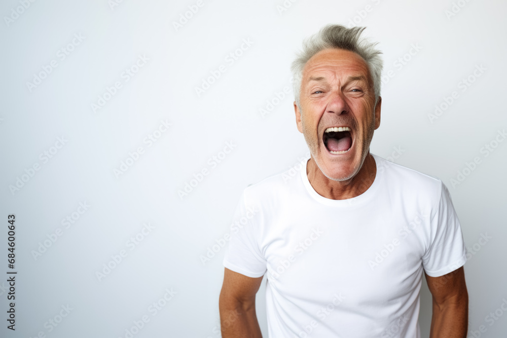 Portrait of a mature good looking man screaming, white and neutral teeshirt and background, anger Portrait of a mature good looking man screaming, white and neutral teeshirt and background, anger