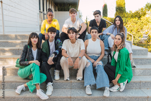 Group of diverse friends sitting on stairs of building in daylight