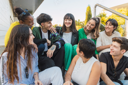 Cheerful group of diverse friends sitting in daylight on building stairs