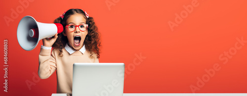 Girl child sit at her laptop and yells into a megaphone. Distance learning, discounts on online courses for kids, promo, online school promotion. photo
