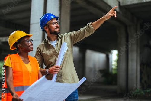 Shot of a young man and woman going over building plans at a construction site. Civil Engineers Checking Works According To Project Using blue prints At Construction Site