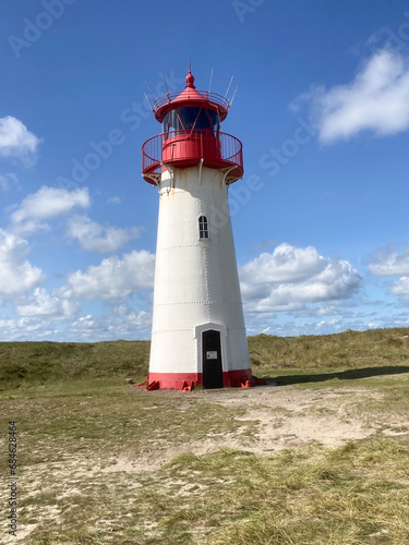 historic Lighthouse on sand dune against blue sky with white clouds on northern coast of Sylt island near List village  Germany