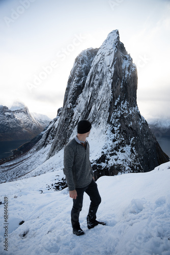 Hiker climbing snowy mountain hike up Segla in Senja, Norway. A man walking up snowcapped mountains in the Arctic Circle of Northern Norway. Famous hike on Senja island. Shot in October