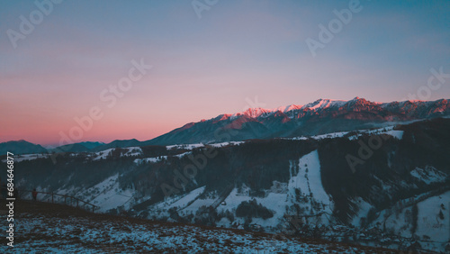 Winter landscape with high and snowy rocky mountains. Amazing sunset in shades of purple in the evening sky © badescu