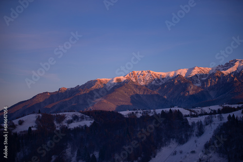 Winter landscape with high and snowy rocky mountains. Amazing sunset in shades of purple in the evening sky