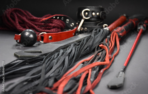 Leather flogger whip sex toys on a dark background stock photo images. Set of erotic toys for BDSM stock photo. Adult sex toy, flogger, ball gag, handcuffs, rope stock images