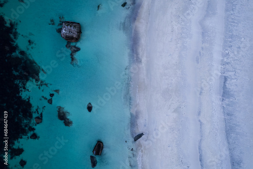 Aerial of Haukland beach in Northern Norway located in the Arctic Circle. This was shot on a drone in the fall. This beach has white sand, crystal turquoise clear blue water, and large rocks.