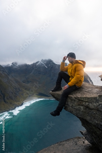 Man in yellow jacket at Kvalvika Beach at sunset in Lofoten, Norway in the Arctic Circle. One of Norway's most beautiful beaches. with tower cliffs and large waves.