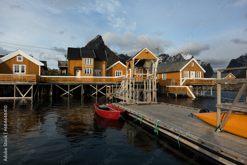 The fishing village of Hamnoy in Lofoten, Norway.  Image shot on a mirrorless camera located in the Arctic circle.  An entire small fishing villlage with yellow houses along the Arctic ocean.