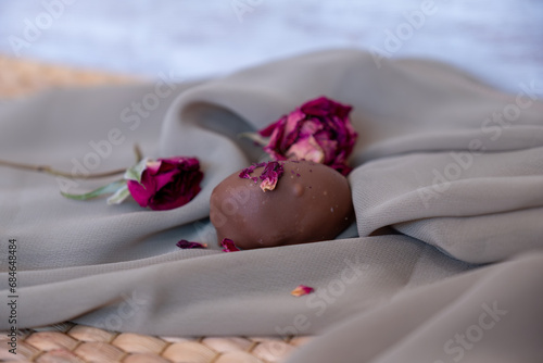 Chocolate pieces with flowers and roses on pink and white background also with mock up space